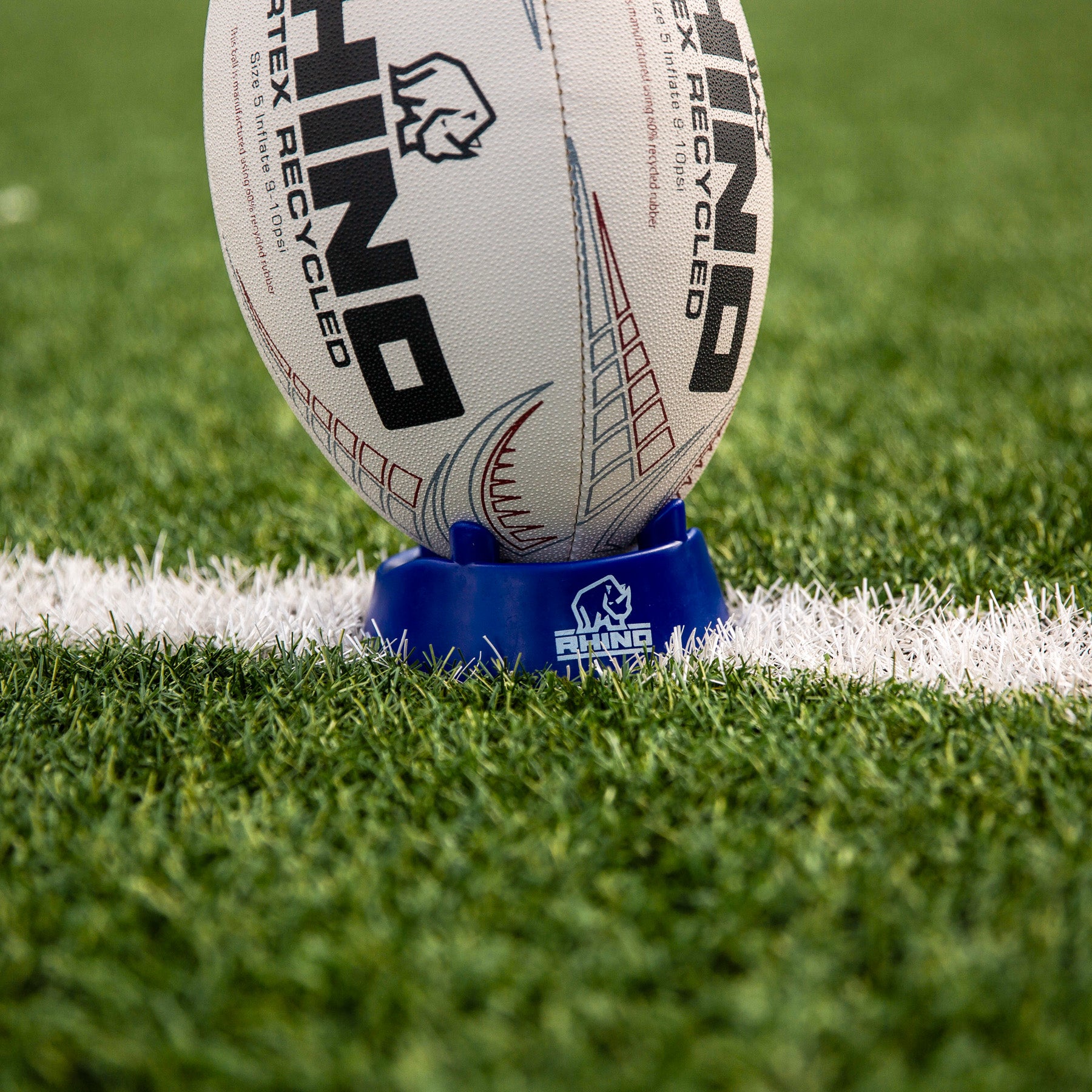 rugby ball on a tee with 'Rhino' branding on a grass field