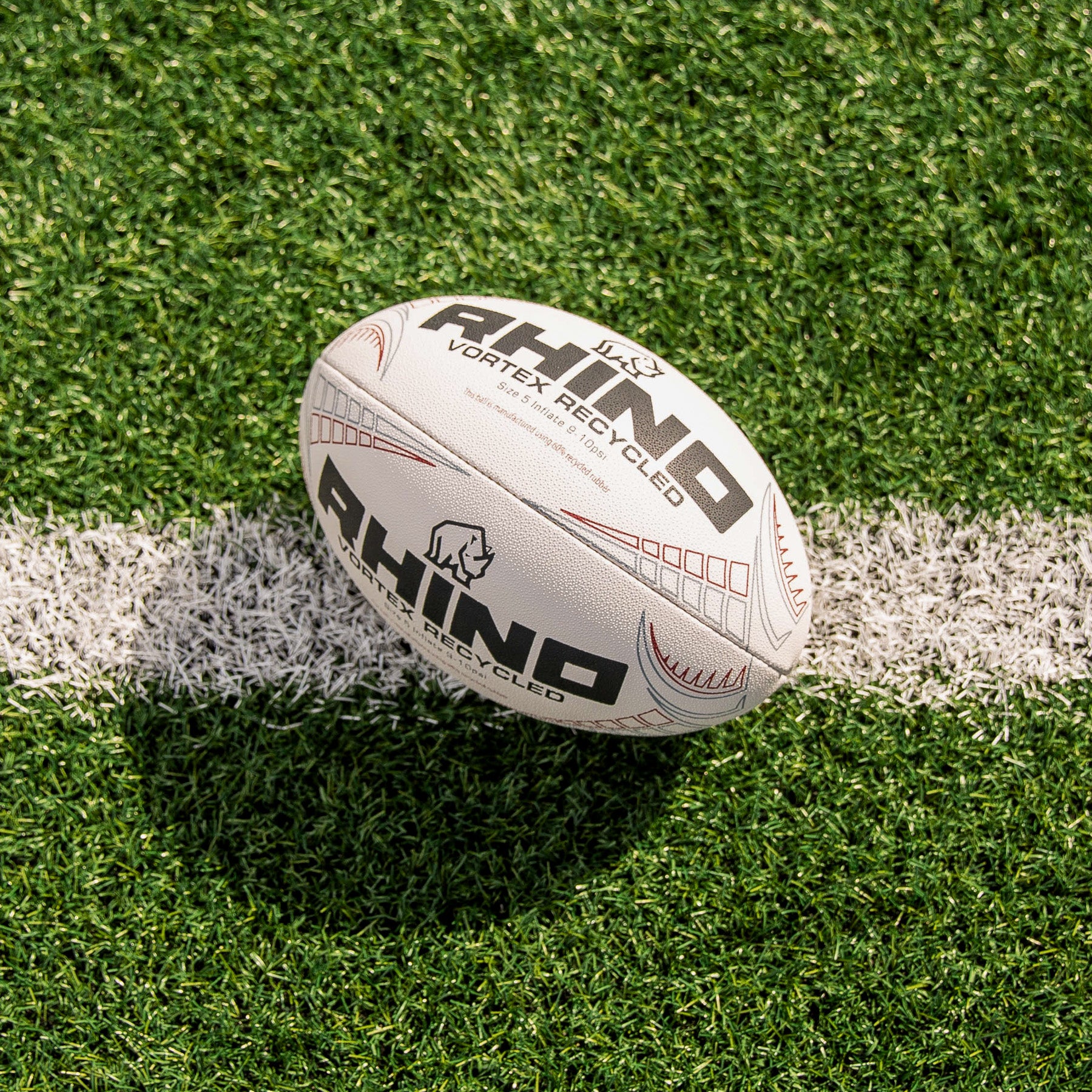 White rugby ball with 'Rhino' branding on a grass field