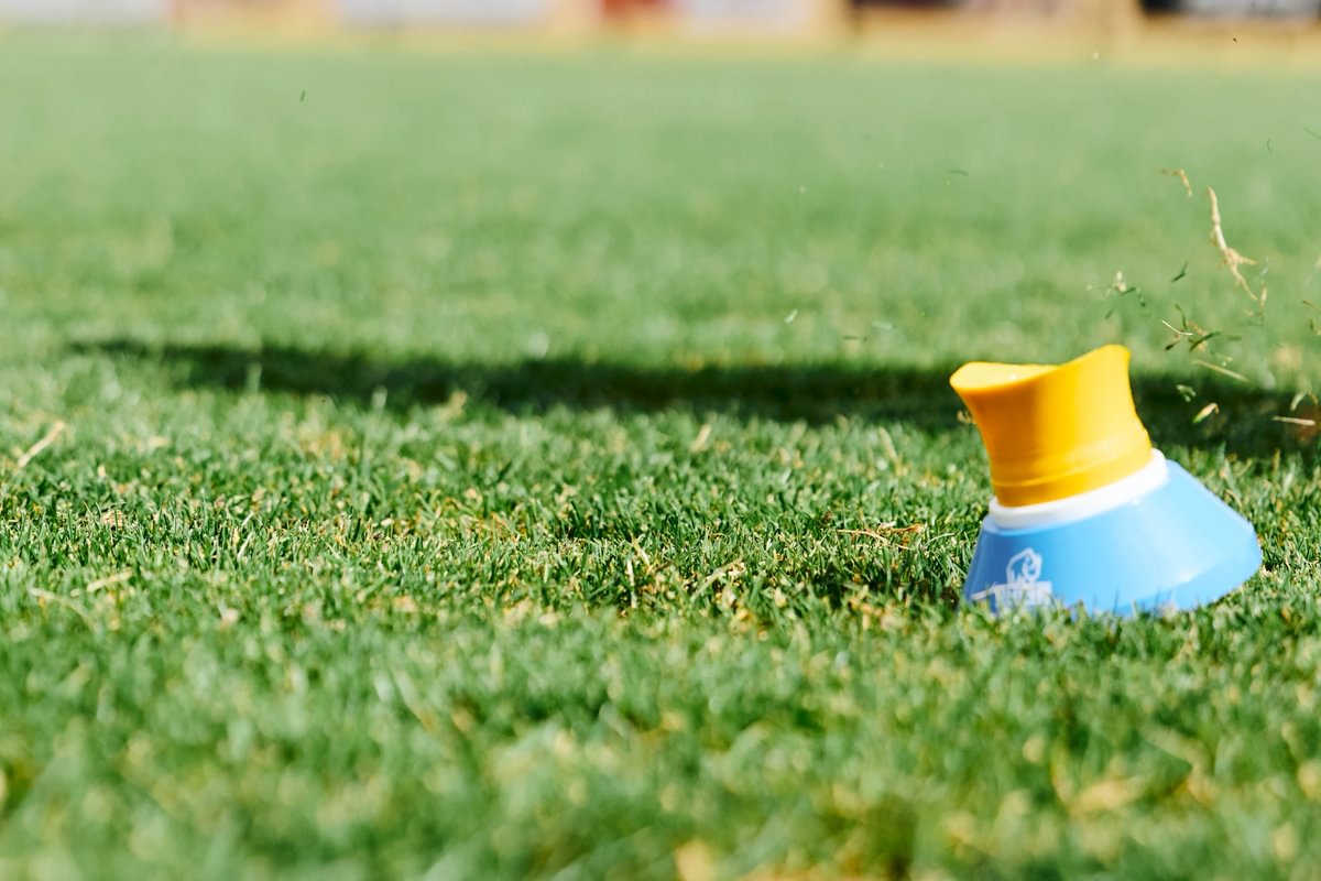 Blue and yellow rugby kicking cone on a grassy field