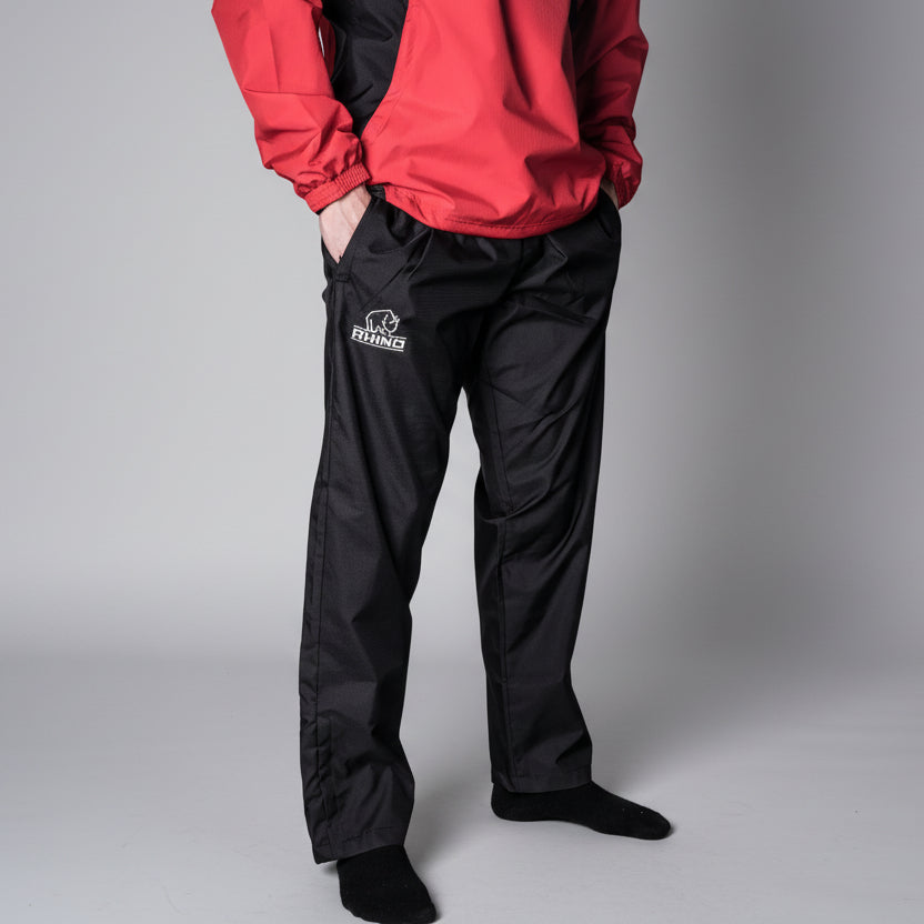 Person wearing a red jacket and black pants with a Rhino Rugby logo on a gray background