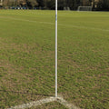 White pole on a grassy field with a goalpost in the background